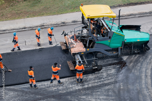 Asphalt paver machine or paver finisher  places a layer of fresh asphalt. Road renewal process, construction working. Collage, unrecognizable workers. High angle view.
