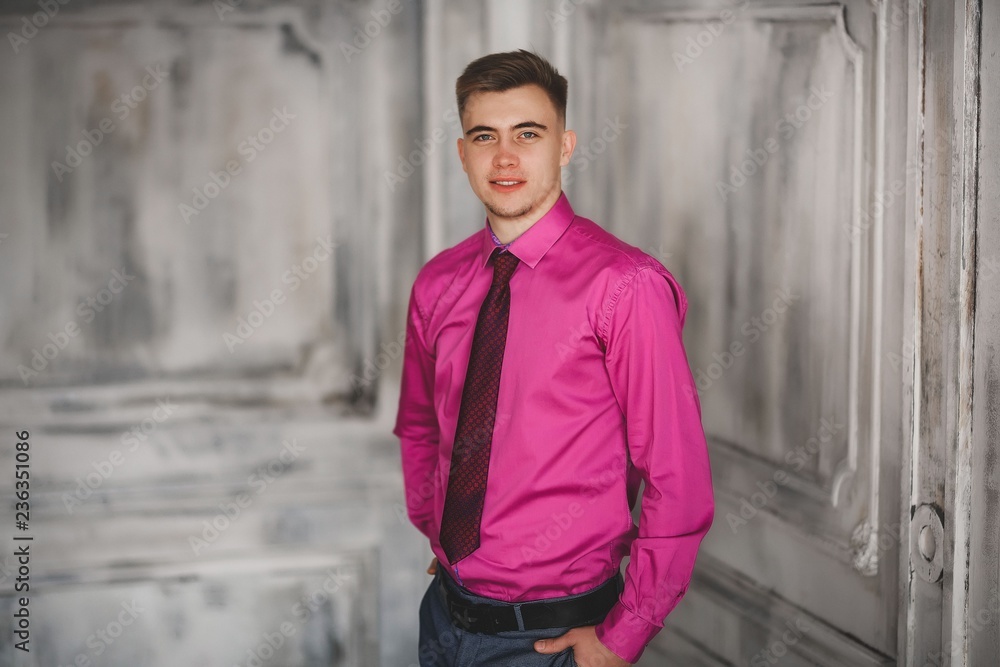 A young man in a pink shirt and a suit.