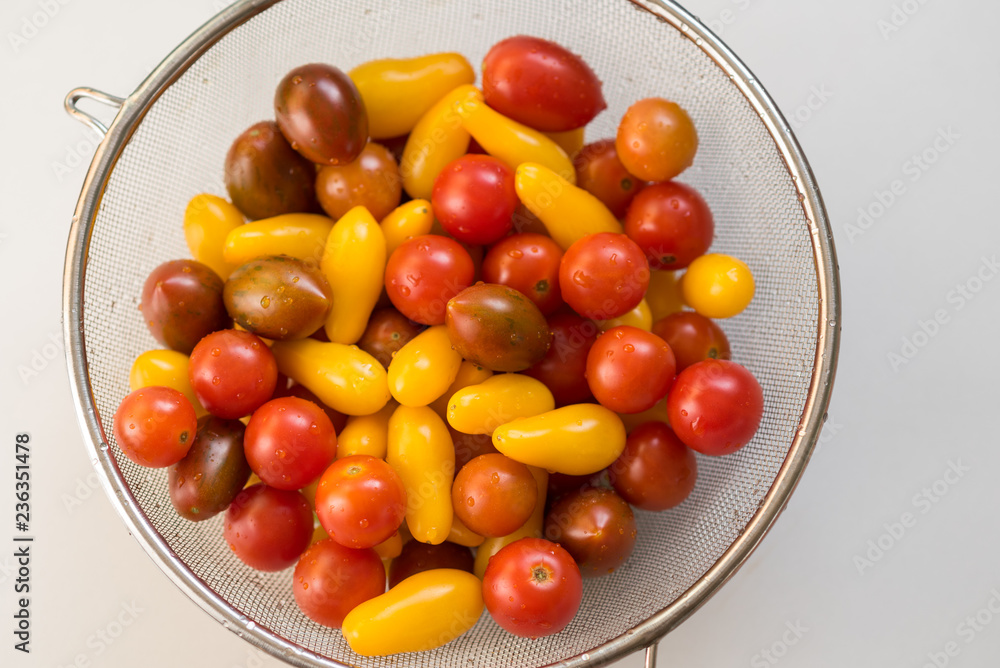 Colorful, healthy foods.Clean, fresh, washed Colorful Cherry tomatoes in a colander. Drops of water on vegetables. Important to wash vegetables before eating concept.