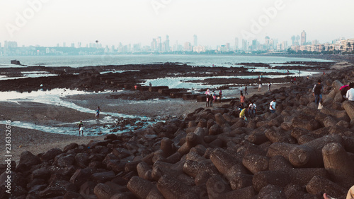 People looking out to sea during the setting sun by the wave breaker in Mumbai, India