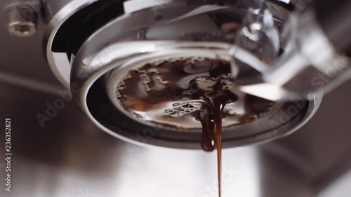 Pouring coffee stream from professional machine in cup. Barista man making double espresso, using filter holder. Flowing fresh ground coffee. Drinking roasted black coffee in the morning. photo