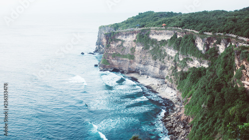 Sun setting over temple in Uluwatu, Bali on the cliff photo