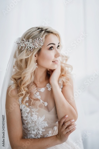 Beautiful blonde bride in a modern dress posing in the Studio. Morning newlyweds.