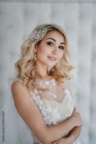 Beautiful blonde bride in a modern dress posing in the Studio. Morning newlyweds.