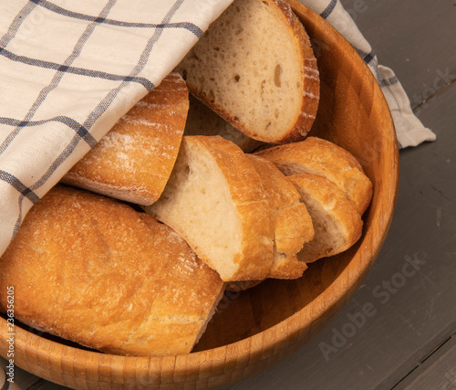 Нарезанный белый хлеб в миске под полотенцем