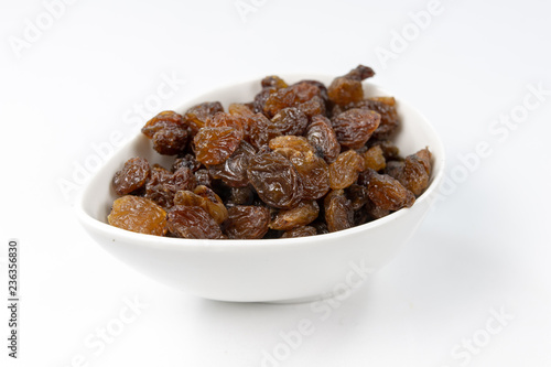 Tasty raisins in a white bowl. Treats for cakes on the kitchen table.