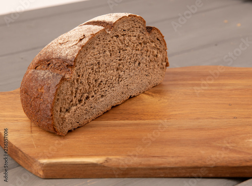 Половина буханки черного хлеба на доске