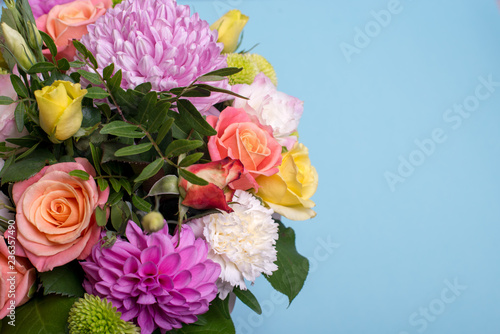 beautiful floral arrangement  pink and yellow rose  pink eustoma  green and pink chrysanthemum  white carnation  pink dahlia on a blue  turquoise background with space for text.