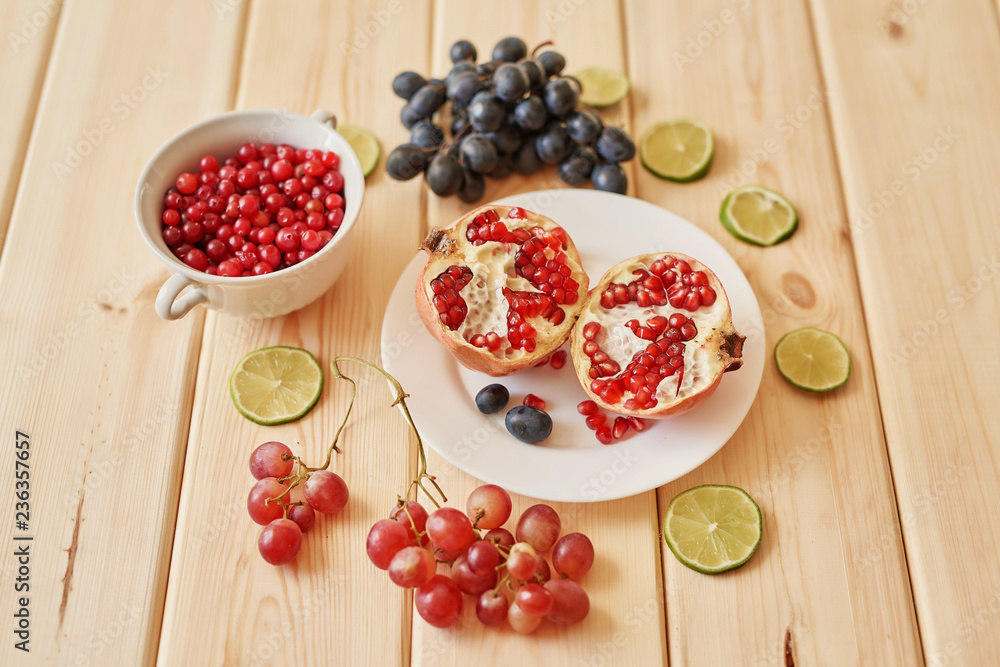 pomegranate, grapes, lime and cranberries on a wooden surface pomegranate, grapes, lime and cranberries on a wooden surface