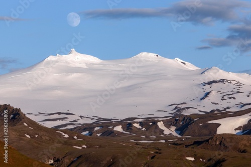 Snow-covered Snaefell volcano with Snaefellsjokul glacier and full moon, volcanic landscape near Hellissandur, Snaefellsnes peninsula, western Iceland photo