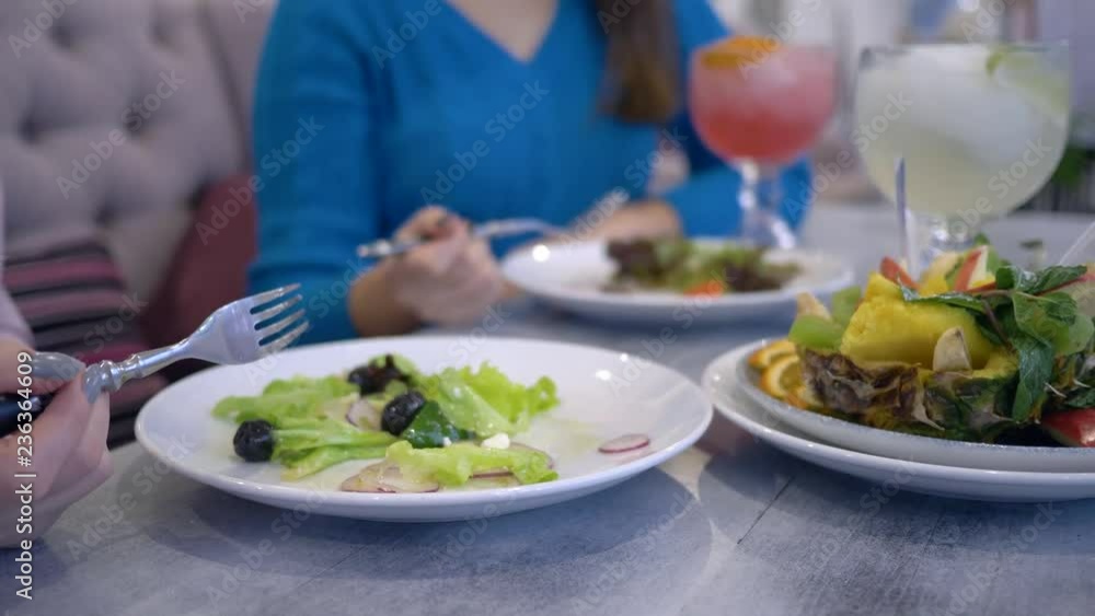 wellness lifestyle, young women on a diet eats greek salad from white plates sitting at the table in cafe wellness lifestyle, young women on a diet eats greek salad from white plates sitting at the table in cafe