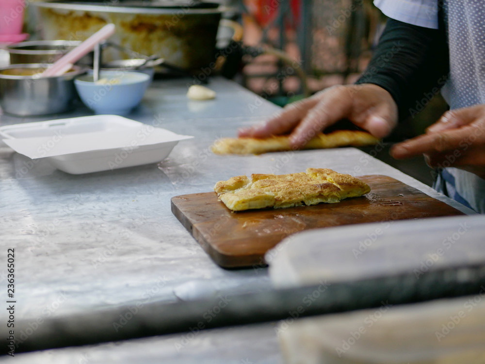 Crisp fresh chopped roti being put in a box getting ready to be served - delicious street food in Thailand