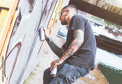 Photography Graffiti artist painting with a color spray can on the wall in the city - Young