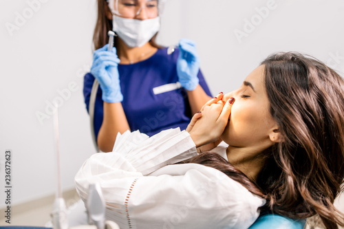 Girl holding hands for sore teeth in the dental room
