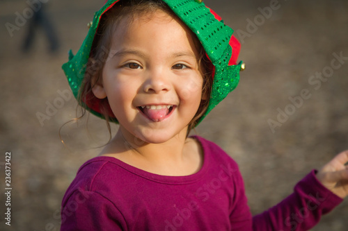 Cute Mixed Race Young Baby Girl Having Fun Wearing Christmas Hat Outdoors