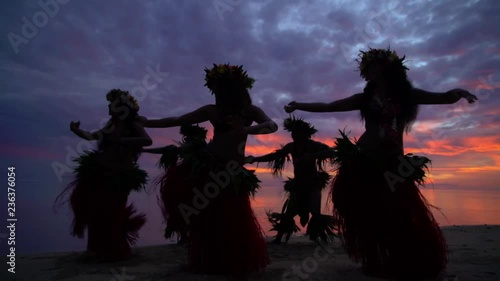 Young males and females in a group of Tahitian hula dancers performing at sunset on the beach barefoot in traditional costume Tahiti French Polynesia South Pacific