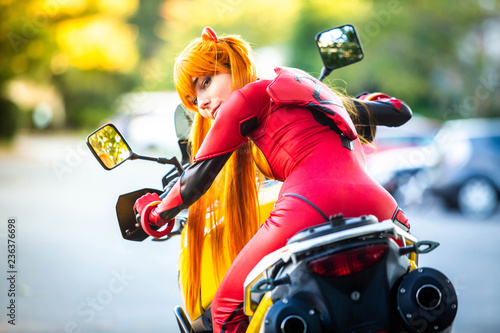 Young attractive girl in red posing with big motorcycle photo