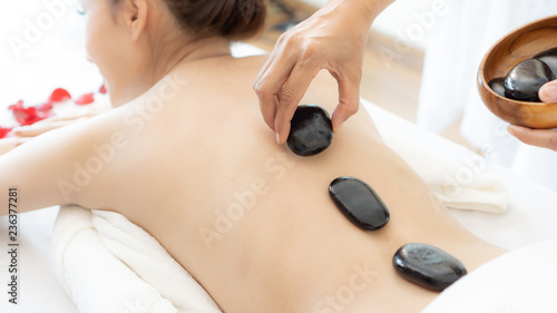 beautiful and healthy young woman during a back stone therapy massage in spa salon