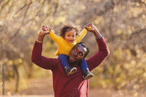 Portrait of happy african dad little boy smiling in the garden.