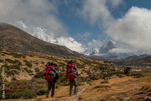 Canvastavla Nepali porters carrying large loads of bags on his back along a track from Dingboche to Everest base camp