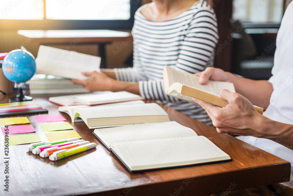 Young students classmates help friend catching up workbook and learning tutoring in a library, education and school concept Young students classmates help friend catching up workbook and learning tutoring in a library, education and school concept