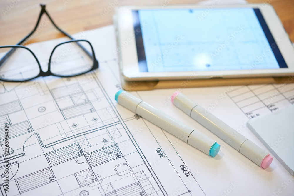 Markers, tablet computer and construction plan on table of architect Markers, tablet computer and construction plan on table of architect