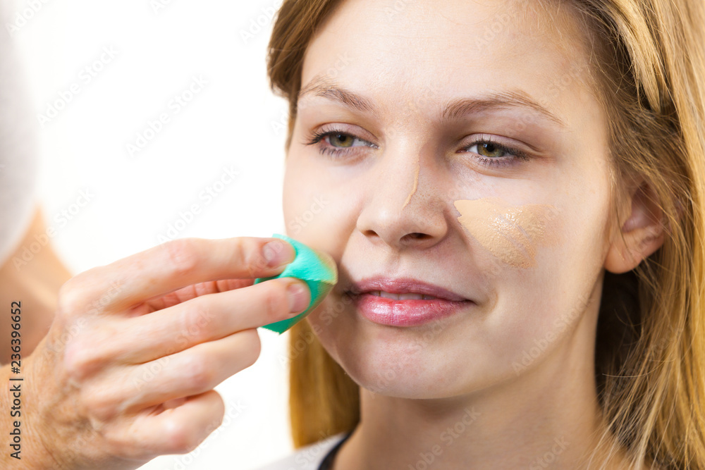 Woman applying foundation with sponge Woman applying foundation with sponge