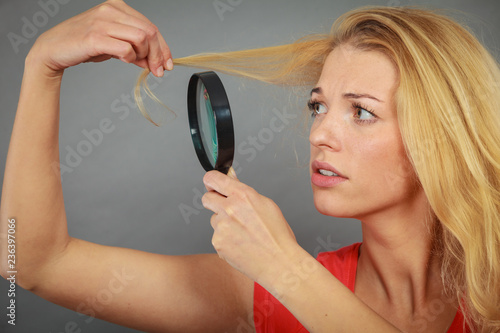 Woman looking at hair through magnifying glass