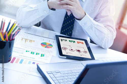 Businessman looking into a modern computer screen reviewing a return on investment or business performance with colourful graphs. photo