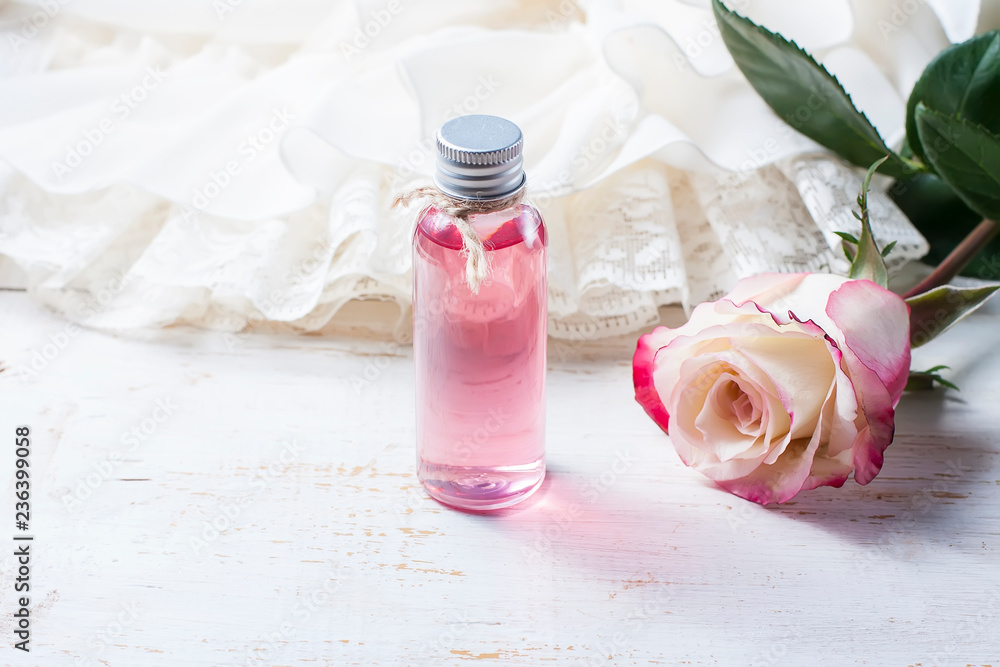 perfumed rose water in a bottle on a wooden table