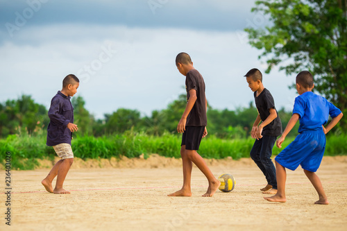 An action picture of a group of kid playing soccer football for exercise in community rural area under the sunset. © nateejindakum