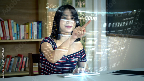 Young Asian teenage girl typing on a futuristic concept wireless keyboard using a holographic head up display computer terminal to surf the net and search for online informations and communication