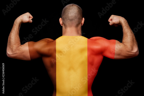 The back of a young sports man wearing a T-shirt with the national flag of Belgium on a black isolated background. Concept of national pride and patriotism
