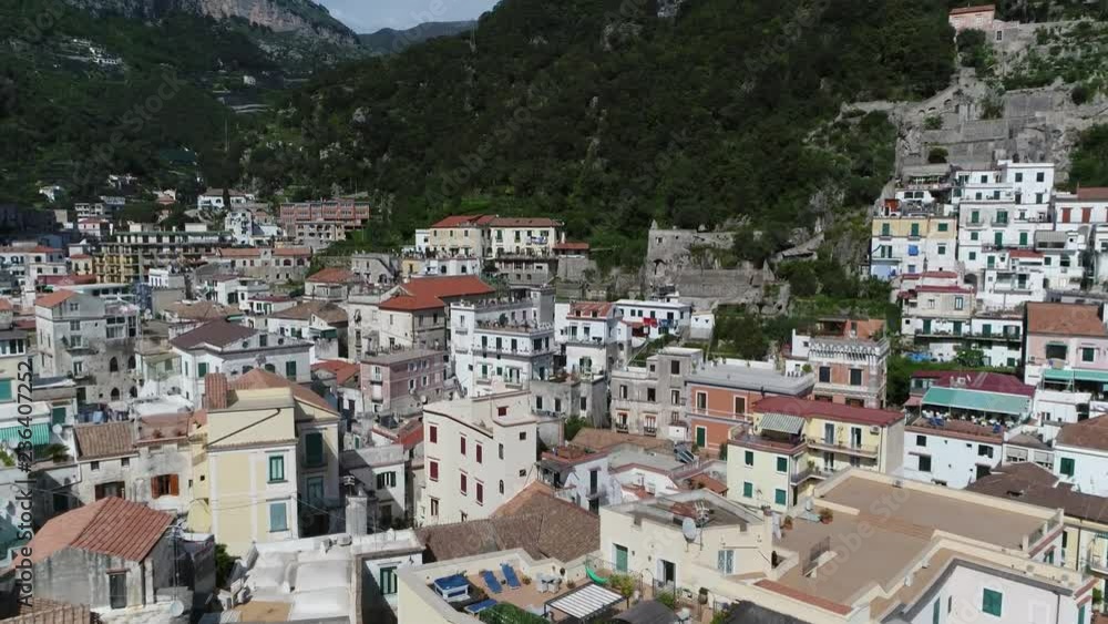Aerial flight over of rural mountain town moving over buildings and bed and breakfast roof terrace showing several seats for sun bathing and relaxing in background tall mounts surrounding urban area Aerial flight over of rural mountain town moving over buildings and bed and breakfast roof terrace showing several seats for sun bathing and relaxing in background tall mounts surrounding urban area