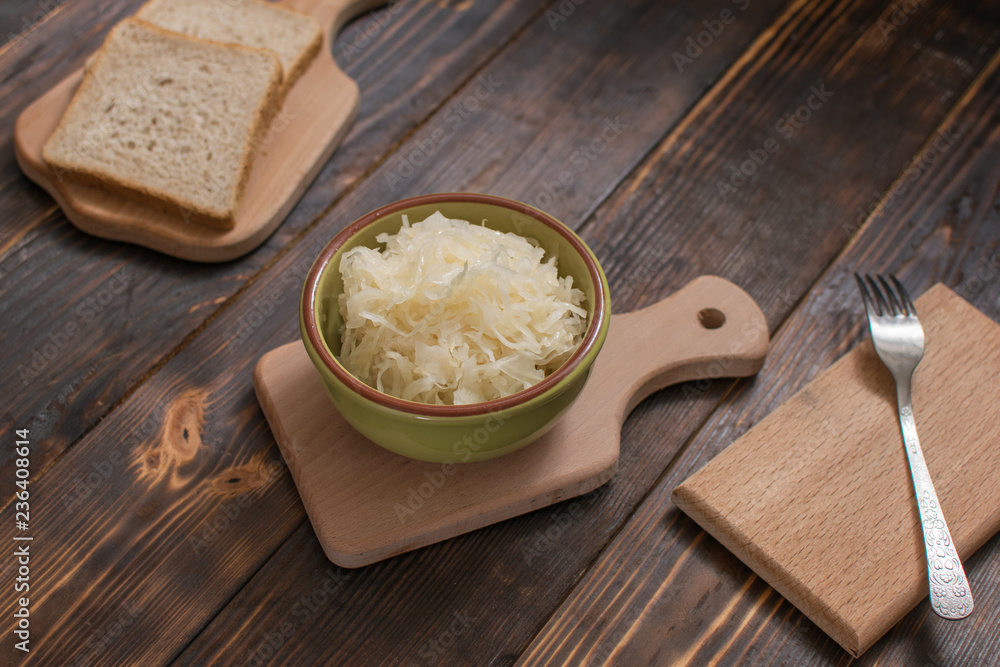 Sauerkraut in a plate and a piece of bread on a wooden background. Sauerkraut in a plate and a piece of bread on a wooden background.