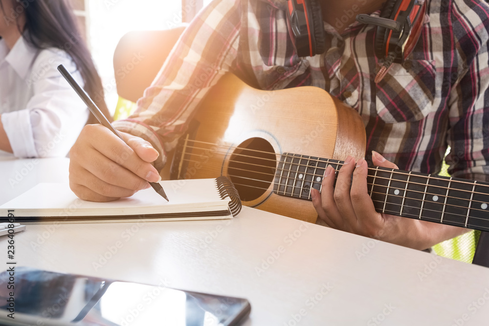 Fototapeta premium Close-up image of composer examining sheets with notes musician songwriter working with guitar and notepad paper.