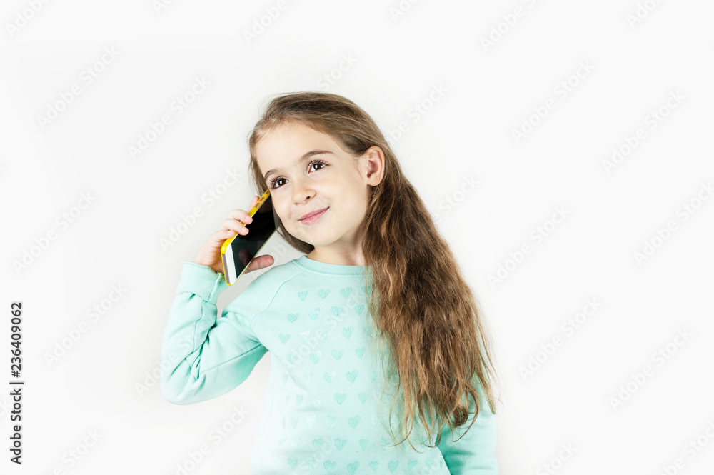 Bright beautiful little girl with the phone is emotionally surprised on an isolated background. Bright beautiful little girl with the phone is emotionally surprised on an isolated background.