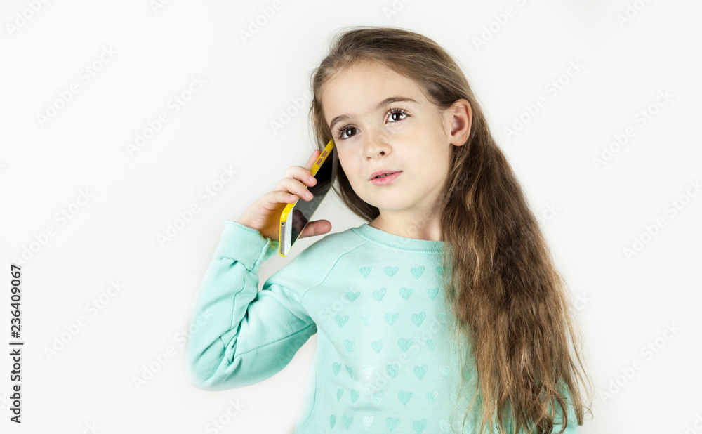 Bright beautiful little girl with the phone is emotionally surprised on an isolated background. Bright beautiful little girl with the phone is emotionally surprised on an isolated background.