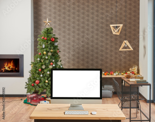 Modern Christmas blur background and new year tree close up desktop screen on the wooden desk.