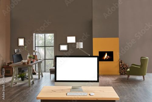 Brown office room working table with fireplace blur background, close up desktop screen on the wooden desk. © UnitedPhotoStudio