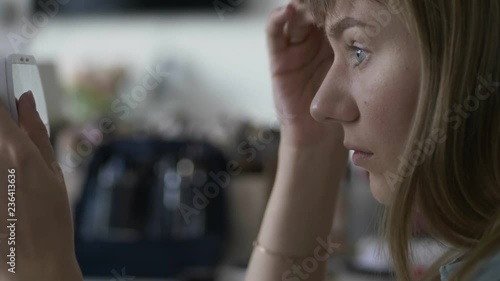 Young beautiful blonde woman applying eyebrow contouring on her face doing professional trendy makeup indoors.