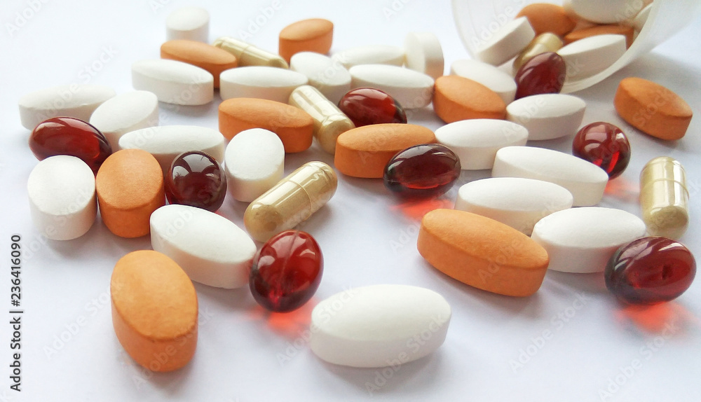 Spilling colorful pharmaceutical medicine pills, tablets and capsules in jar on white background. Pharmacy theme, health care, drug prescription for treatment medication and pharmaceutical medicament Spilling colorful pharmaceutical medicine pills, tablets and capsules in jar on white background. Pharmacy theme, health care, drug prescription for treatment medication and pharmaceutical medicament
