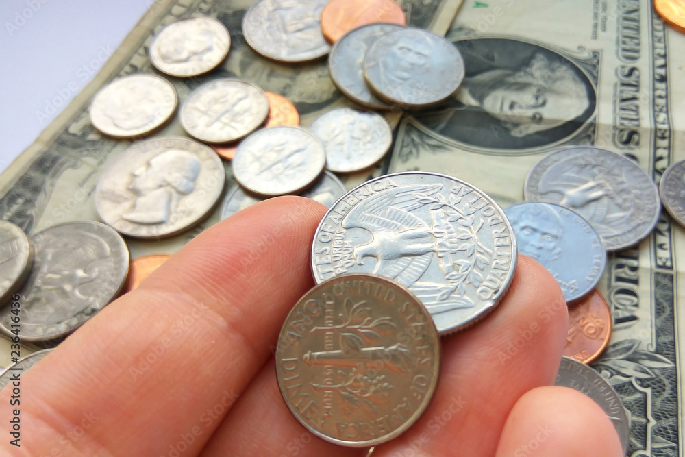 Close up American quarter, dime and penny coins in hand on two dollars usa background Close up American quarter, dime and penny coins in hand on two dollars usa background