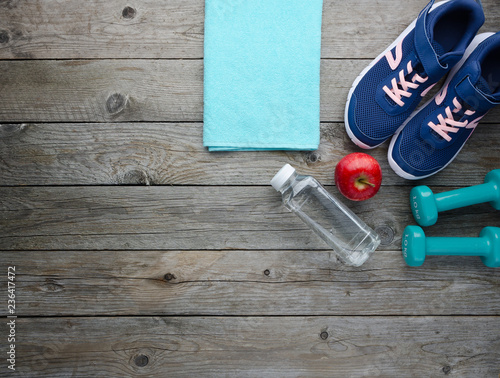 Sneakers dumbbells bottle of water and apple