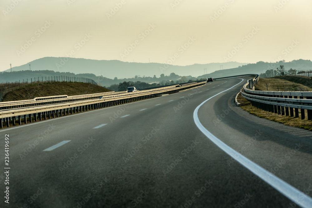 Fototapeta premium Winding Highway through Rural Landscape with few cars on a cloudy Overcast Day