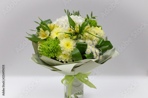 Bouquet of fresh flowers (yellow green) in paper packaging on a light background