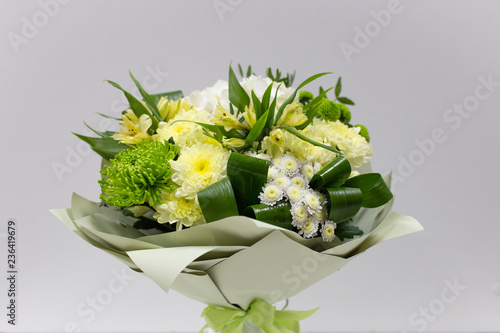 Bouquet of fresh flowers (yellow green) in paper packaging on a light background