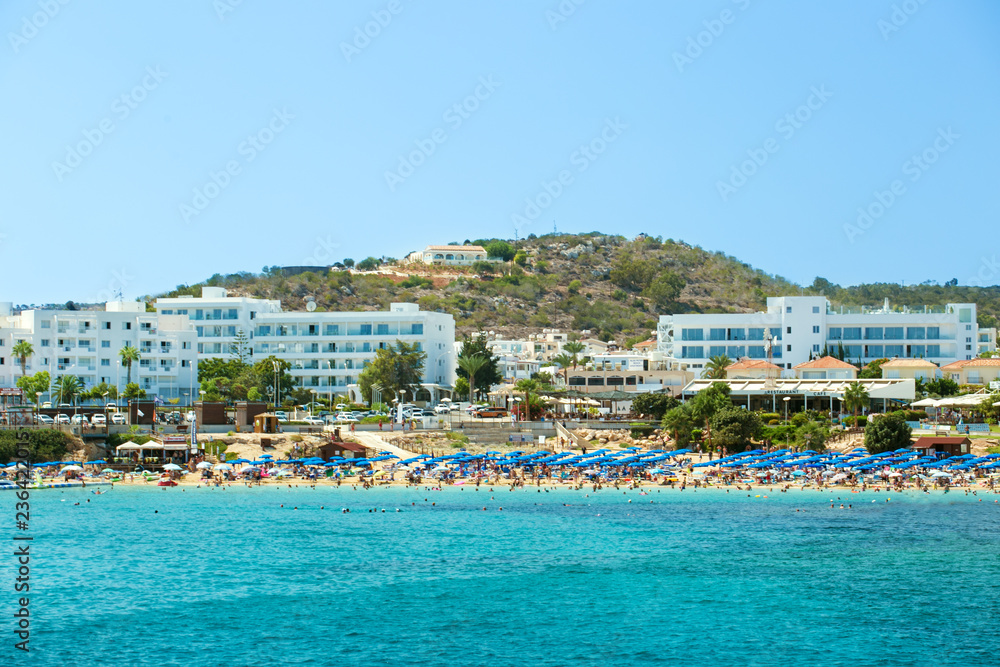 Photo of sea and fig tree bay beach in protaras, cyprus with swimming people and hotels.