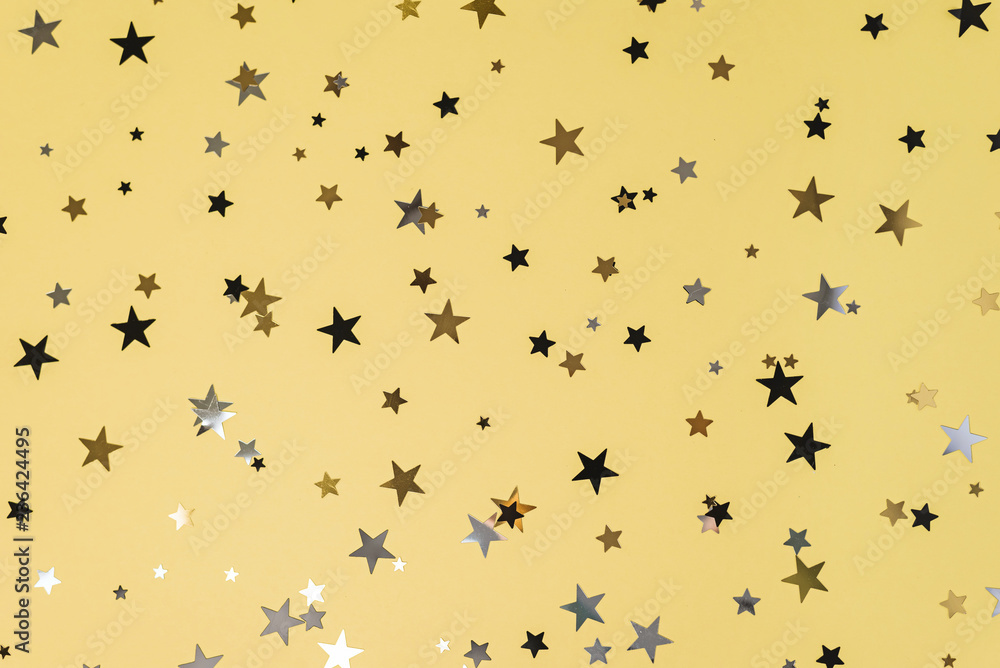 Delicate glitter star confetti on yellow background. Delicate glitter star confetti on yellow background.