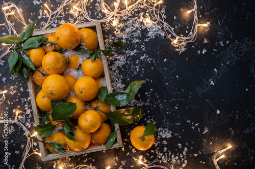 Photo of tangerines in wooden box on black table